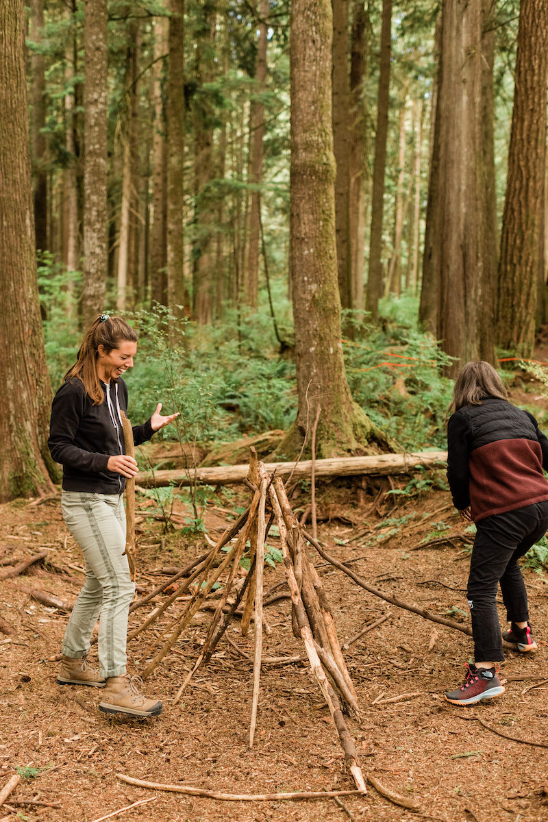Adults doing a team building exercise and building a structure out of sticks in the Malcolm Knapp Research Forest