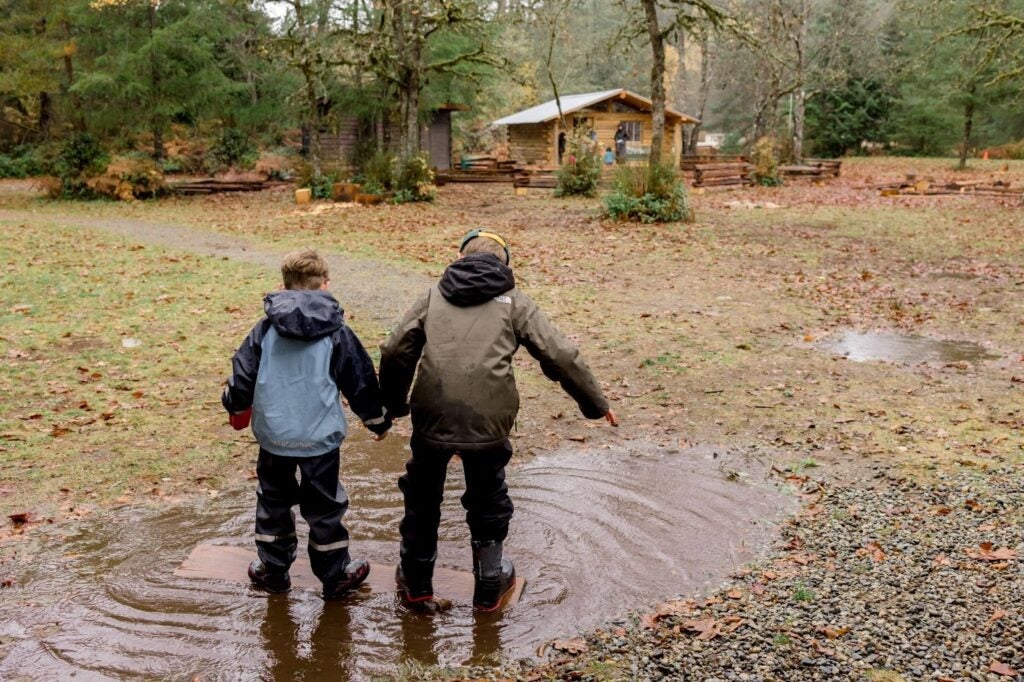 kids playing in a puddle on a rainy weather day at the research forest