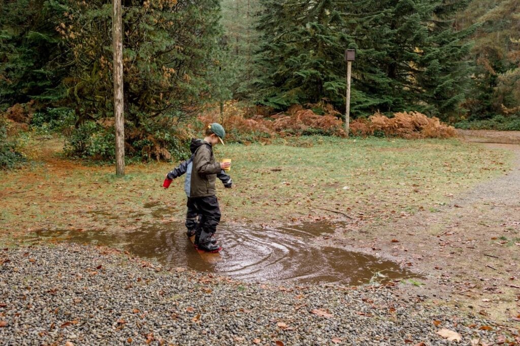 two young boys playing in a puddle in maple ridge, wearing waterproof clothing on a rainy day