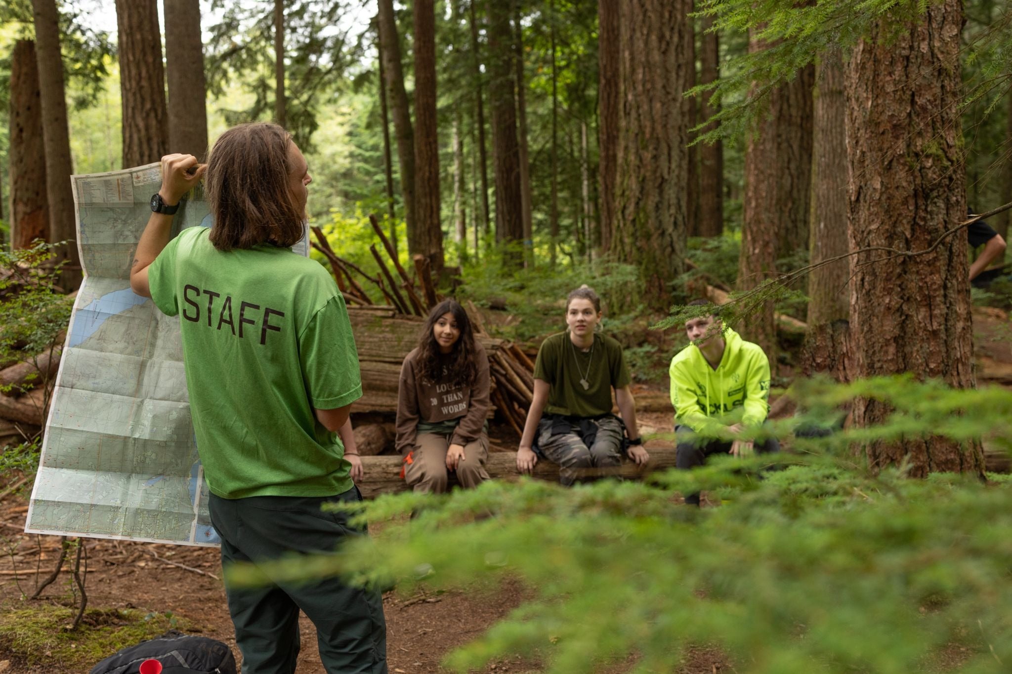 a teen camp group leader holding up a map and teaching participants about forest navigation