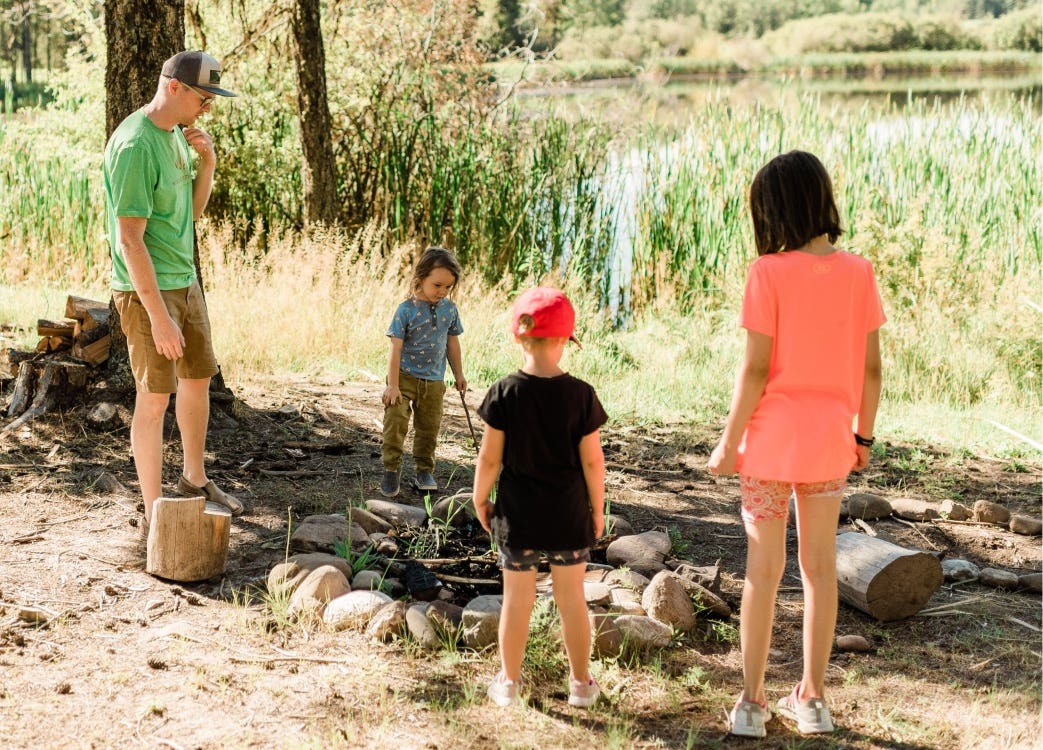 Young kids around a campfire in the forest during the day