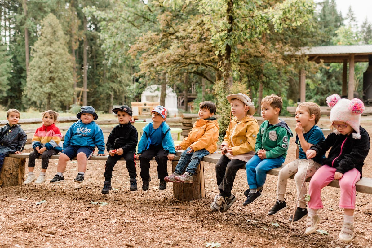 Kids sitting and listening during wild & immersive forest school events in williams lake