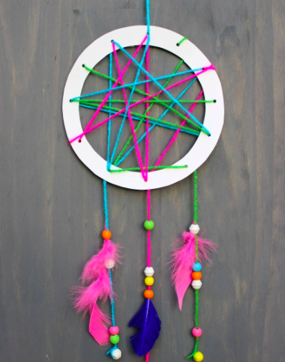 nature craft of a dreamcatcher using a paper plate as the circle ring, and yarn and beads as the interior and hangings with feathers on the ends