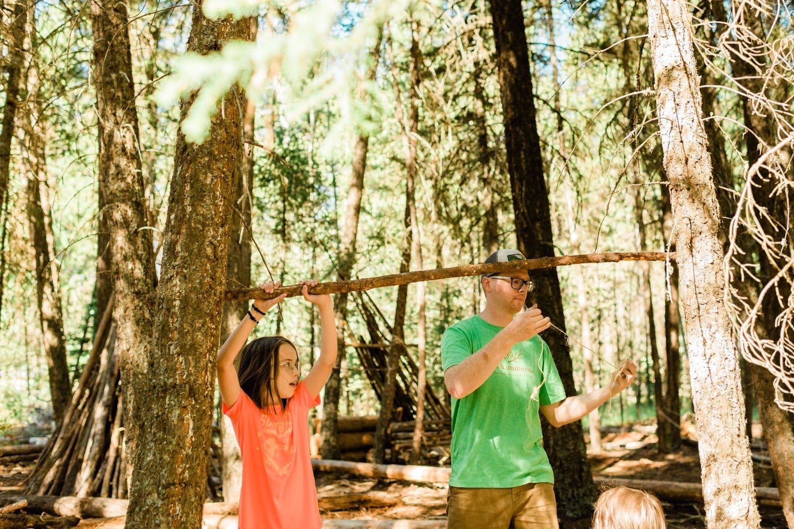 a group leader and child at a Williams Lake outdoor learning program, creating a structure with sticks in the Alex Fraser Research Forest