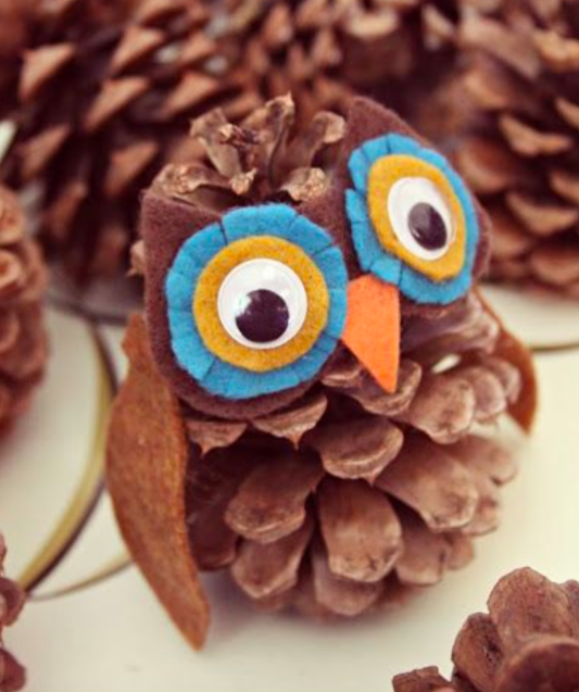a nature craft DIY pinecone owl with a pinecone body, wobbly eyes and felt feathers and wings
