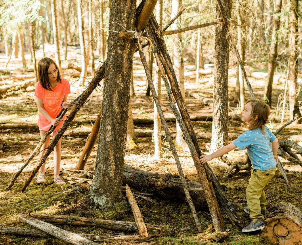 Two kids building stick structure in the forest