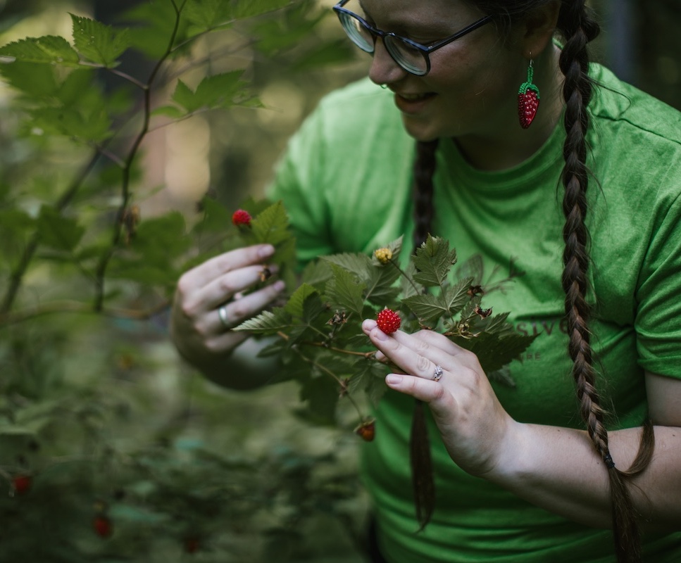 Wild & Immersive leader holding up wild raspberries in the forest
