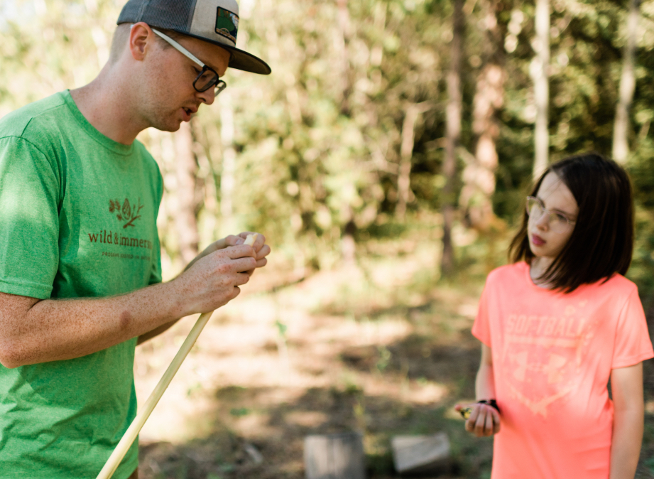 Wild & Immersive leading showing a child how to carve a stick at a williams lake pro-d day camp
