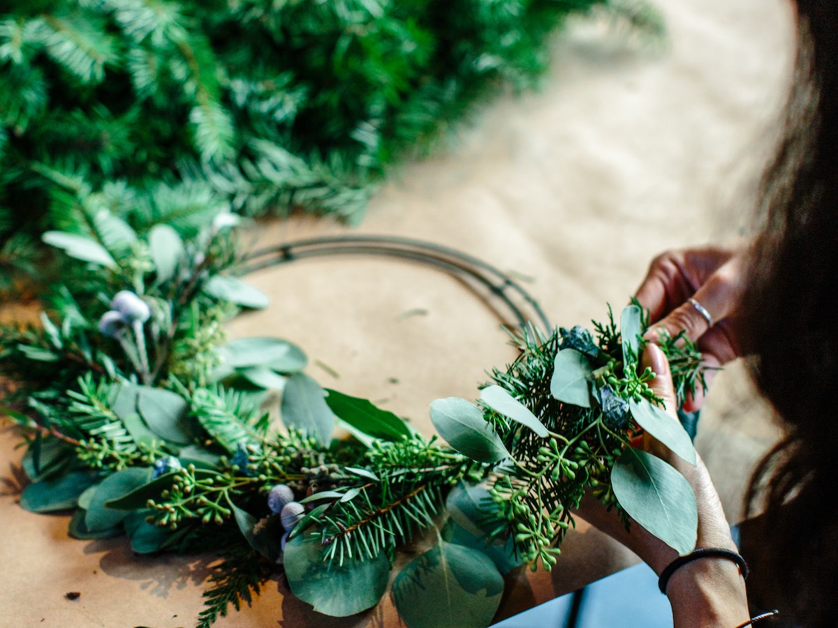 a woman adding greenery to a wreath during a wreath marking workshop