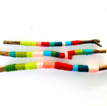 sticks with yarn wrapped around in colourful stripes of red, greens, blues, and greens